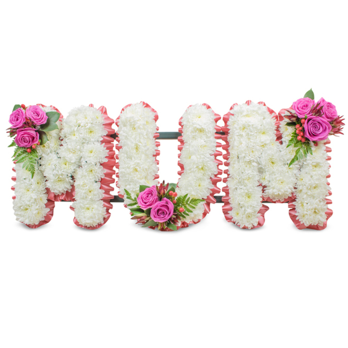 Crafted with a steady hand and thoughtful restraint, this standing floral tribute spells MUM in large, capital letters formed almost entirely from pristine white chrysanthemums. The many small, tightly packed mums create a dense, velvety surface that reads pure and comforting against a bright white background. Each letter is bordered with a subtle ruffled trim of soft pink ribbon, a delicate halo that introduces warmth without overwhelming the purity of the white blooms. A dark green support structure is visible between the letters, a reminder of the professional mounting that keeps the display upright and composed for viewing at a service.

Three coordinated sprays of fuchsia-pink roses, glossy green fern-like foliage and clusters of reddish-orange hypericum berries are artfully positioned: a bouquet at the top left of the first M, a second tucked into the lower curve of the U, and a third placed on the upper right of the final M. The roses offer a velvety scent and a heartfelt colour accent, while the mums provide the quiet, traditional note often chosen for sympathy flowers. As a local florist in Finsbury, Finsbury Flowers prepares this kind of personalised tribute for memorial services, wakes or graveside dedications; its composition is especially suited to peaceful settings such as Finsbury Square or nearby City Road venues. The overall effect is one of restrained elegance - a respectful and loving farewell that honours a mother with clarity, texture and gentle colour.