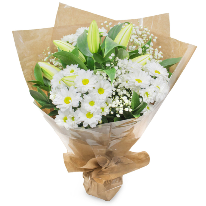 A graceful bouquet of white and green, artfully composed to read as both fresh and quietly celebratory, is pictured against a pure white background. The primary visual note comes from numerous white chrysanthemum blooms: each head made of many fine, radiating petals around a pale yellow centre that adds a warm point of focus. Interwoven among these are several upright, pale green lily buds-tall, tapered and often faintly streaked-many still tightly closed and promising a later, softer bloom. Wisps of baby's breath (Gypsophila) float between the larger flowers, their tiny white florets creating an airy, cloud-like texture that softens the bouquet's silhouette. Dark glossy foliage and longer green stems provide a verdant framework, making the whites appear crisp and luminous. The gathering is hand-tied and wrapped in two layers: an inner crinkled brown kraft paper that brings an organic, market sensibility, and an outer clear cellophane that reflects light and protects the delicate petals; the wrapping is folded and secured at the base to form a neat, stable support. In soft daylight the arrangement gives off a faint, clean fragrance-notes of green stems and a hint of floral sweetness-suitable for a calm anniversary, a thoughtful condolence, or a fresh welcome for a new home near Old Street or Exmouth Market. This bouquet reads as confident, composed, and quietly optimistic, made with the steady hand of a local florist who understands simple gestures of care.