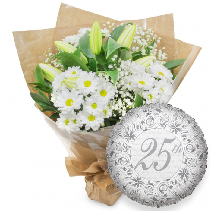 This image portrays a beautifully composed Silver Anniversary floral arrangement with a coordinating balloon, photographed against a clean, all-white background that brings out every tonal nuance. On the left side, a lush, hand-tied bouquet of white blooms steals the focus, much as it would if placed on a dining table in a Finsbury home before a special anniversary meal. Clusters of white chrysanthemum daisies form the bulk of the arrangement; their petals are crisp and orderly, radiating around bright yellow centres that add a soft, cheerful glow. Emerging through this bed of daisies are several long, pointed white lily buds. They are still closed, with a faint flush of green at their edges, suggesting quiet promise and the slow unfolding of fragrance and beauty over the coming days. Interspersed among the main flowers are delicate sprays of white baby's breath, their countless tiny blossoms forming light, airy clouds that soften the structure and add dimension. Deep green foliage cradles and surrounds the blooms, the leaves arching naturally and providing contrast, much like the mature trees and greenery that frame Finsbury's squares and streets. The bouquet is wrapped with care: an inner layer of clear cellophane hugs the stems and reflects soft highlights, while an outer layer of natural brown kraft paper, slightly textured and artfully folded, offers a rustic yet refined touch. The stems are gathered tightly and secured at the base, presenting the bouquet as ready to be carried up the stairs of a townhouse or delivered across EC1. To the lower right, gently touching the edge of the flowers, is a round silver foil balloon. Its surface shows the characteristic fine wrinkles of foil, catching light in a subtle metallic shimmer. At the centre of the balloon, the inscription 25th appears in an elegant, flowing script, enclosed by ornate silver scrolls and stylised floral motifs that lend a classic, almost vintage character. Behind this, the words Happy Anniversary repeat in pale grey, creating a soft background pattern. Together, the bouquet and balloon present a harmonious tribute to twenty-five years together, understated yet unmistakably festive.