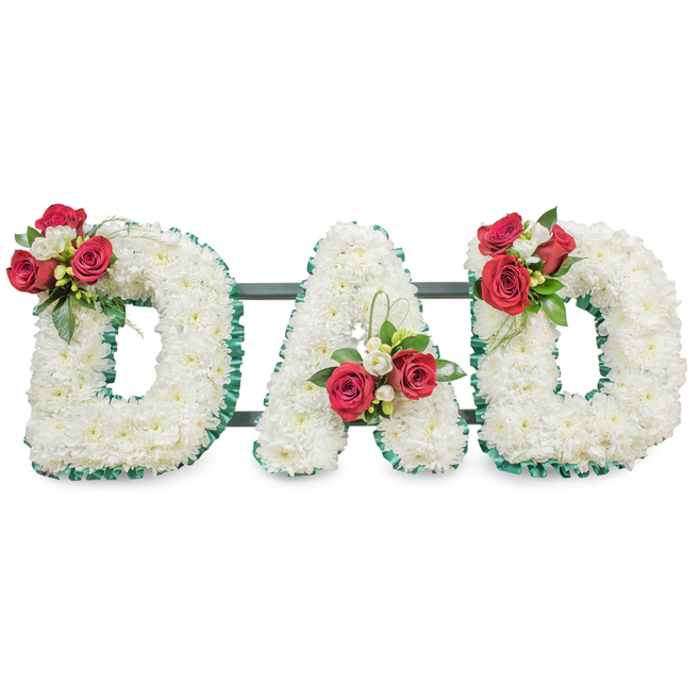 A poignant, handcrafted floral tribute that spells DAD in three three-dimensional capital letters, each densely covered with pristine white chrysanthemums so tightly packed they form a smooth, cloud-like plane of soft petals. The white surface is precisely outlined with a ribbed, emerald-green ribbon that adds a crisp graphic edge to each letter and frames the composition with refined contrast. Thoughtfully composed floral clusters accent each letter: on the upper left curve of the first D a bouquet of deep red roses - some in tight buds, some opening - sits alongside clusters of small white freesia and lush dark-green foliage, lending a focal point of warmth and texture. The A is adorned with a like cluster positioned near the lower left stem, complemented by a slender loop of bright green foliage that introduces a subtle vertical lift and contemporary movement. The final D mirrors the first, another grouping of red roses, white freesia and verdant leaves resting gracefully on its upper curve to create visual harmony across the trio. Narrow, dark green support bars run behind the letters, discreetly linking them and ensuring stability for display at a funeral chapel or graveside service. Bathed in soft, even light against a clean white backdrop, the arrangement reads both solemn and tender - a classic sympathy statement that balances traditional meaning with modern simplicity. For families in Finsbury and neighbouring streets around Finsbury Square, this kind of personal tribute offers a tactile, fragrant way to honour a father's memory with respect and love.