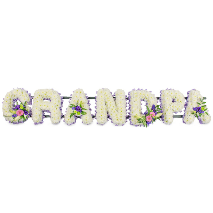 This image presents a personalised sympathy tribute spelling out GRANDPA in seven strong, upright capital letters, designed with the care and precision of an experienced Finsbury florist. Each letter is constructed from densely packed white chrysanthemums or similar multi-petalled blooms, arranged so close that they form a seamless, cushioned surface. The soft, rounded petals catch the light, giving the tribute a luminous, peaceful quality that feels appropriate for a funeral or memorial service. Around each letter runs a fine border of smaller lilac and lavender-toned flowers, creating a crisp outline that separates the letters from the plain white background and allows the word to be read easily from across a chapel or graveside near Finsbury, Angel, or King's Cross. Select letters feature accent sprays that add colour and a sense of personal story: on the 'G', a cluster of vibrant pink blossoms is paired with an elegant white lily-like flower and fresh green foliage, drawing the eye gently to the start of the word. The first and last 'A' show more modest posies of purple blooms and deep green leaves, while the 'D' holds a more prominent cluster that echoes the pink, white, and green tones seen in the 'G'. Occasional bright green button chrysanthemums introduce a light, uplifting note within the more traditional palette. A slender, dark green bar runs horizontally behind all seven letters, almost hidden beneath the flowers but crucial for supporting and aligning them as a single, coherent tribute. Overall, the design conveys respect, affection, and calm remembrance, making this Grandpa letter arrangement a fitting floral expression of love and gratitude from the family.