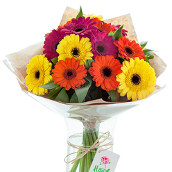 Nestled within a clear, elegantly shaped vase, this vibrant Gerbera daisy bouquet showcases a symphony of colour that mirrors the energetic spirit of Finsbury. Each stem is thoughtfully placed by local hands-golden yellows, tangerine oranges, and velvety magentas rise together, each bloom swirling with life. Dark centers form a bold contrast to the brilliant petals, while leafy greens weave through the arrangement, echoing the lush pockets of greenery along Finsbury Square. The Blooms are embraced by a crinkled wrap of light brown kraft paper and then protected by glossy cellophane, their layered textures hinting at the meticulous craftsmanship of Finsbury Flowers. The stems are visible through crystal-clear water in the vase, a testament to freshness. A natural twine, tied in a rustic bow, suspends a classic white gift tag bearing a red rose motif-a subtle nod to the timeless tradition of thoughtful gifting. The overall presentation is both cheerful and soothing, evoking feelings of celebration and gratitude, whether destined for a loved one's special day or to bring new energy into a work space along St John Street.