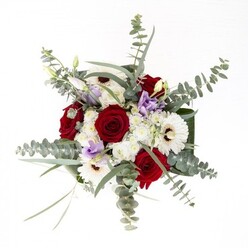 To a florist in Finsbury, this bouquet stands as an emblem of poised artistry-each flower given space to tell its story, yet blending in refined harmony. The creamy, radiant petals of white gerberas, anchored by espresso-hued centers, draw the eye outward from the bold, gracefully spiraled red roses that anchor the design. Lavender-toned lisianthus, interspersed delicately among the more robust blooms, suggest the subtlety of dusk over Myddelton Square. Wisps of eucalyptus arch in gentle curves above, casting a cool-toned shadow across the arrangement and infusing a trace of invigorating fragrance-the kind you might encounter in the quiet corners of local gardens. A frame of glossy, substantial leaves encircles the base, highlighting the arrangement's symmetry. Through the vase's crystal-clear glass, the green stems stand upright in water, a visible testament to freshness and attention to detail. Whether for a joyful anniversary, a thoughtful thank you, or simply to bring a touch of Finsbury's natural beauty into the home, this bouquet is both a visual and sensory delight.