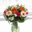 This radiant bouquet, crafted for the diverse homes and hearts of Finsbury, overflows with cheerful peach and vibrant orange gerbera daisies that set a warm, welcoming mood. These playful blooms are complemented by deep magenta roses, their classic spiral inviting a touch of love and celebration. Between the bold colours, white alstroemeria and petite spray roses lend freshness and elegance, their subtle beauty reminiscent of hidden garden nooks along Rosebery Avenue. Broad, glossy aspidistra leaves cradle the flowers in a structured embrace, creating a sense of abundance and serenity. Delicate pink and airy white filler flowers peek through the bouquet, adding movement and fullness akin to spring breezes dancing through the local community gardens. Set in a tall, clear glass vase that gives a glimpse of vibrant green stems, the arrangement glows under gentle, natural light - each colour pristine against a bright, uncluttered background. The ensemble carries the subtle fragrance of roses and lilies, evoking Finsbury's lively yet peaceful character. Perfect for punctuating milestones, showing appreciation, or lifting spirits, this arrangement provides a sensory celebration that echoes the creativity and warmth of Finsbury's neighbourhoods.