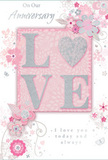The anniversary card pictured here is a tender tribute to long-lasting romance, its design unfolding like a softly spoken promise shared in a quiet corner of Finsbury. At the card's heart, the word LOVE is spelled out in gently raised letters, dusted with a fine layer of glitter that shimmers in pale pinks and silvery whites. The O is replaced by a softly rounded heart, embossed and textured in silver, giving the central motif an extra touch of dimension and sentiment. This focal point rests on a blush-pink panel, subtly shaded so that it glows against the surrounding pale background. From around this central area, delicate blooms in blush, mauve, and creamy white unfurl in gentle arcs, their petals painted with a watercolor softness that blends seamlessly into the soft pastel ground. Fine, sweeping lines suggest trailing vines, tendrils, and wispy leaves, echoing the flowing contours of romantic bouquets delivered by Finsbury Flowers to homes tucked between Old Street and King's Cross. Tiny decorative details - small petals, spiralling flourishes, and faint, ethereal butterflies - add motion and a touch of whimsy, recalling the lightness of a spring breeze moving through garden borders. The colour palette remains restrained and soothing, with soft pinks and silvery greys creating a sense of intimacy and calm. Elegant script phrases such as On Our Anniversary and I love you today and always are thoughtfully placed within the design, their gentle curves harmonizing with the floral swirls. The overall impression is of a card that feels as cherished as a favourite bouquet, perfectly suited to accompany fresh anniversary flowers delivered across the Finsbury area to celebrate years of shared love and quiet companionship.